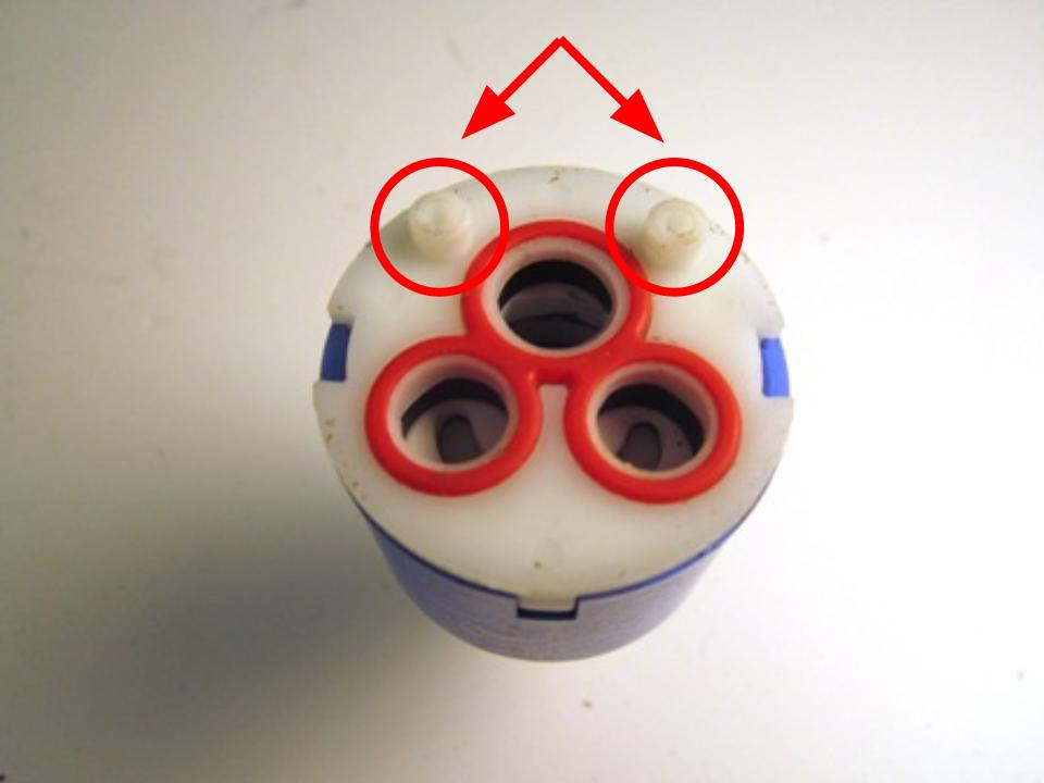 Locate the locating pins on the bottom of the cartridge and locate the corresponding holes in the faucet body.