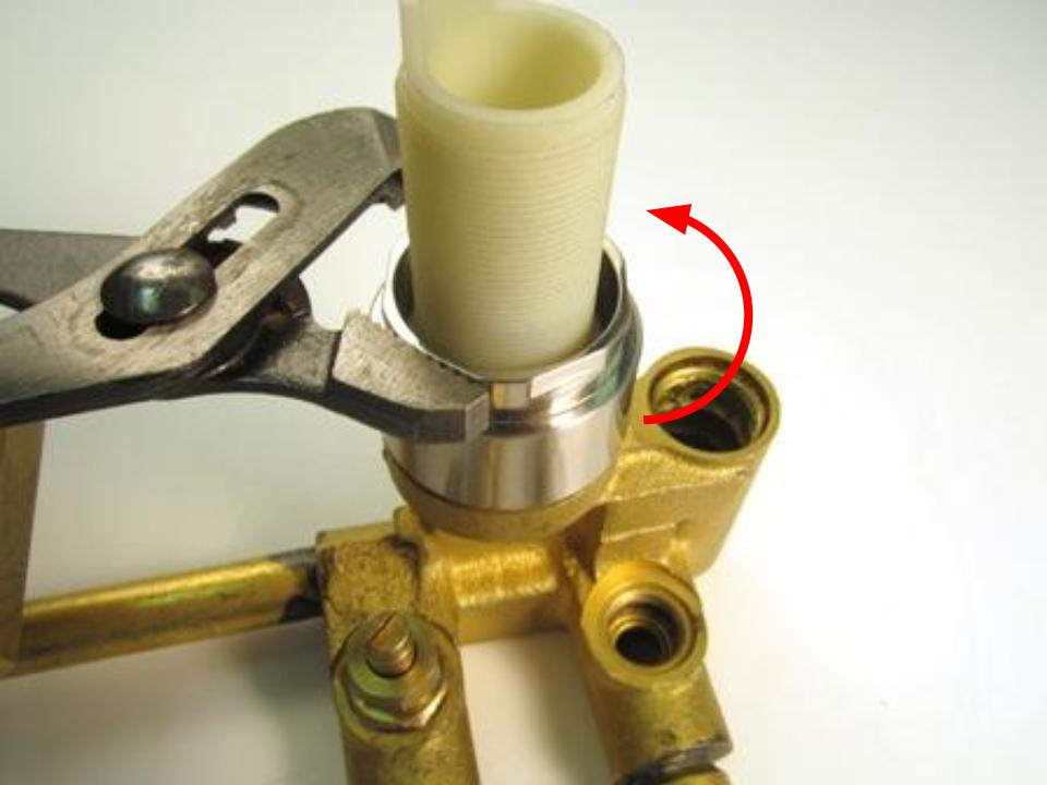 The threaded shank of the cartridge assembly is held to the valve by the he trim ring/locking nut.  This piece has flat sides to accommodate a wrench.  Twist counter-clockwise to remove.  